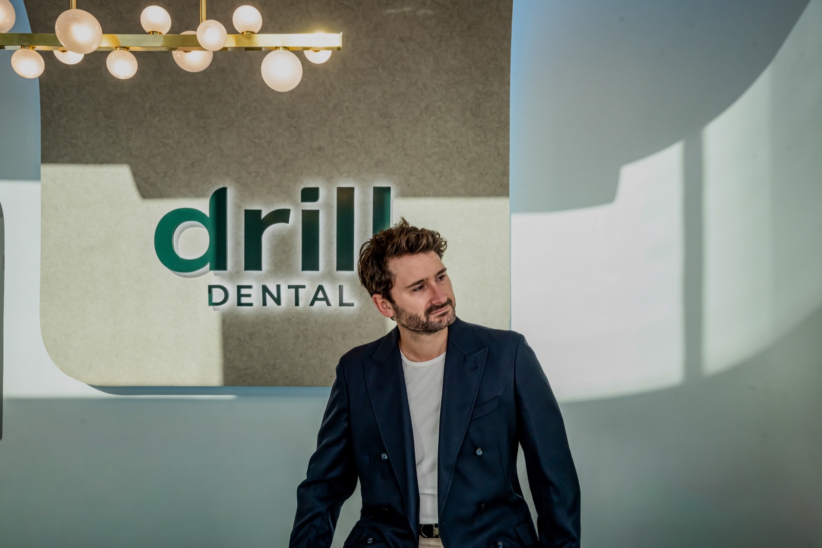 Alex at Drill Dental, in front of the practice sign